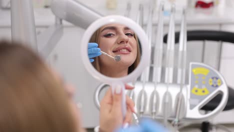 in a modern dental office, a female patient uses a small mirror to carefully examine her smile.