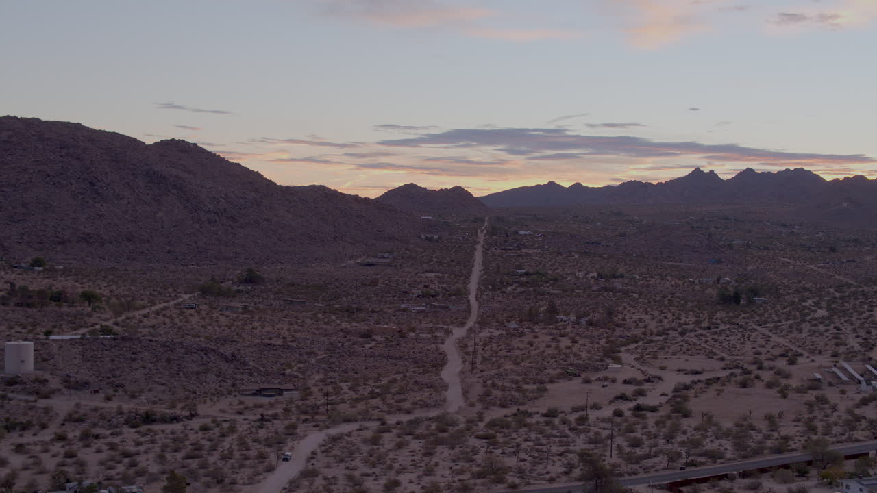 empuje aéreo hacia y sobre un camino de tierra solitario que se dirige hacia las colinas del parque nacional joshua tree en california en una hermosa tarde al atardecer