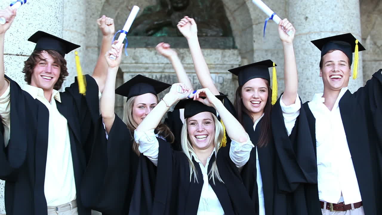 행복한 졸업생들이 팔을 들고 뛰어다닙니다.