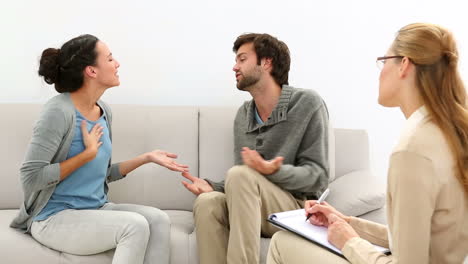 young couple arguing while therapist takes notes