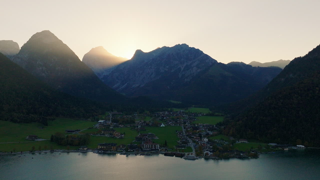 Piccolo villaggio di Pertisau sul lago Achensee con la silhouette all'alba della catena montuosa alpina della regione del Tirolo, ripresa con panoramica aerea