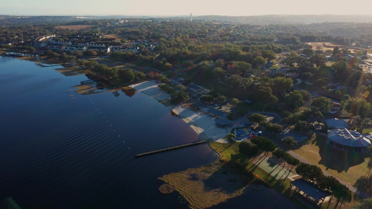 Droneperspektiv av lokalsamfunnet ved Lake Minneola i Clermont, Florida, med brygger, treomkransede bredder og den glitrende blå innsjøen som strekker seg mot horisonten