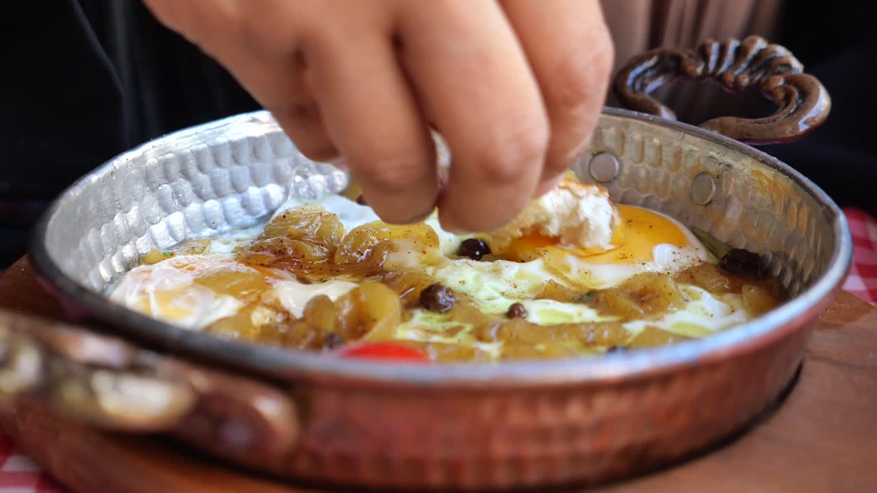 Geleneksel bakır tavada soğanlı lezzetli sahanda yumurtaya ekmek batıran el.