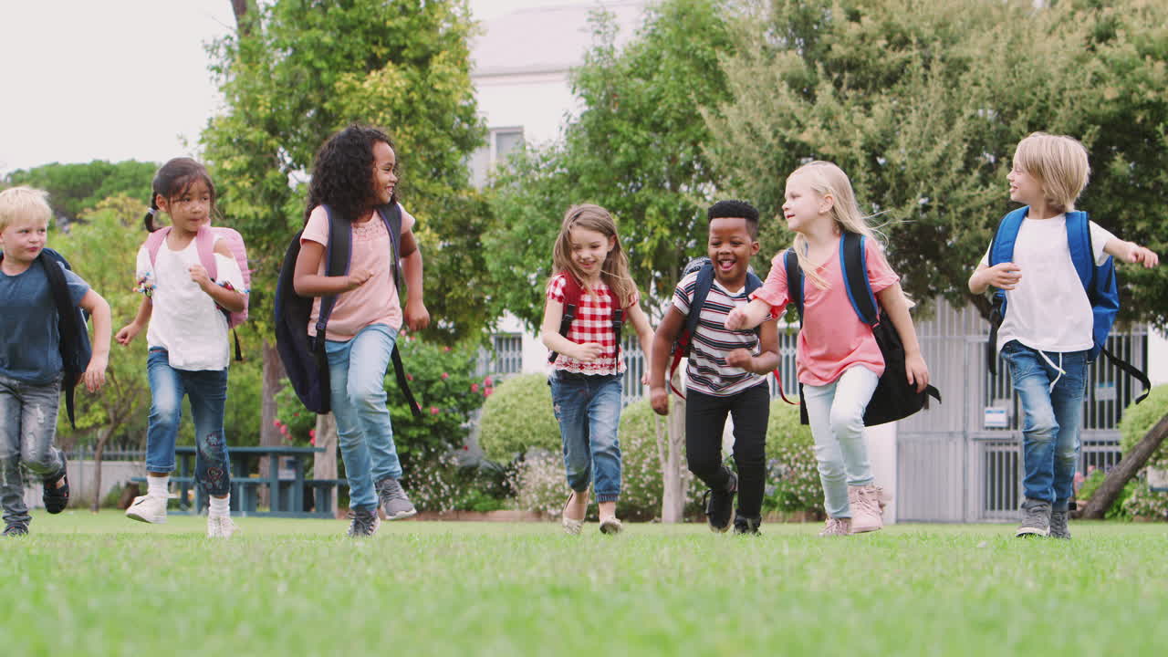 흥분 된 초등학교 학생 들 이 휴식 시간 에 들판 을 가로질러 달리고 있다