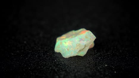 seamlessly rotating a colorful mineral (opal) in front of black background