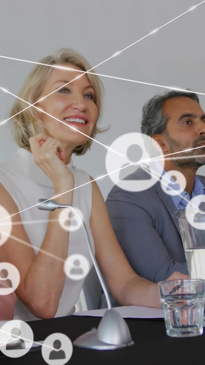 Relatrice che si sporge in avanti parlando nel microfono, stimolando connessioni di business che coprono il pannello durante il discorso