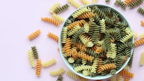 fusilli orgánico que se derrama sobre un fondo rosado