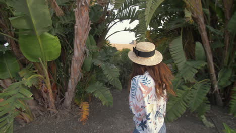 mujer con sombrero de paja caminando por las palmeras