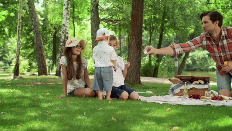 positive parents blowing soap bubbles with children in park