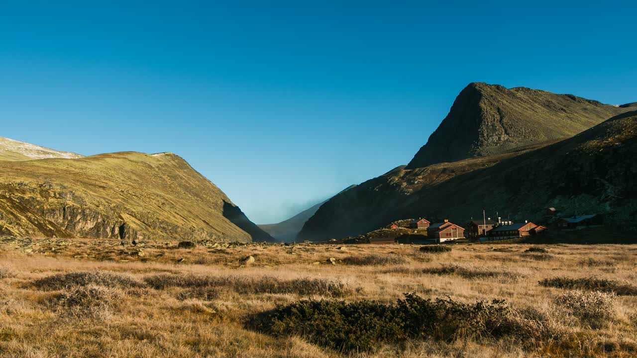 Nebbia mattutina intorno a una splendida valle nel Parco Nazionale di Rondane in Norvegia con sfondo di cielo azzurro e soleggiato - a bassa quota, timelapse