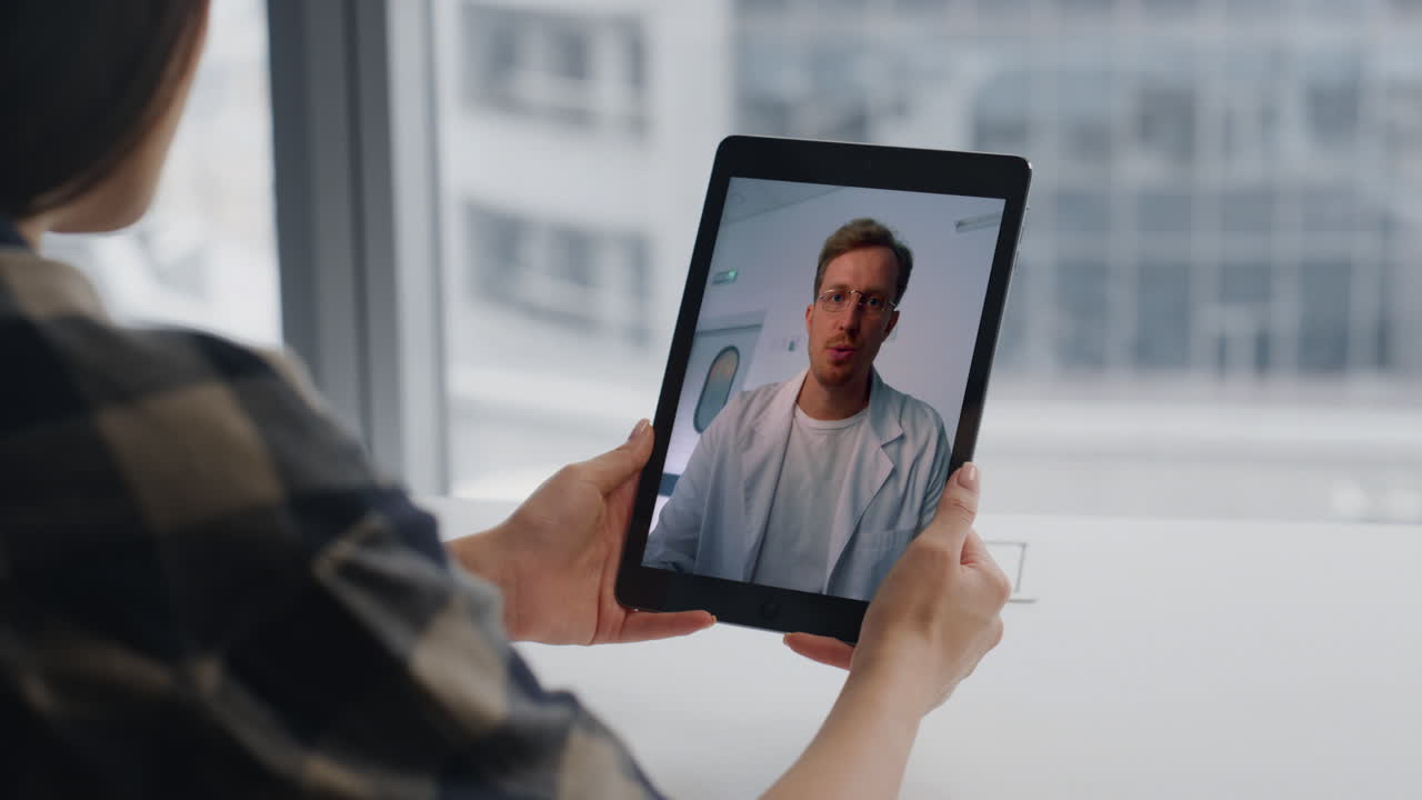 Mani di un freelance che guardano lo schermo di un tablet, primo piano di una stanza con vista sulla città. Dottoressa che chatta