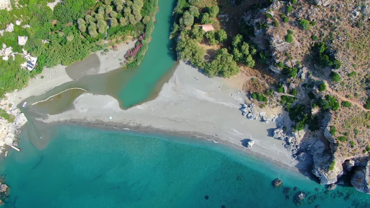 Aerial tilt shot of river Kourtaliotis flowing among mountains towards Preveli beach in Crete, Greece