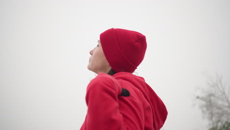 side view of middle-aged woman turning head left under foggy atmosphere, blurred trees in background, misty, serene outdoor scene with focus on gentle movement