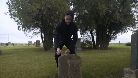 hombre triste, emocional y angustiado arrodillado en la tumba para llorar en el cementerio