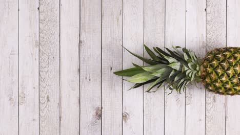pineapple rolling in place on right side of  wooden theme. stop motion