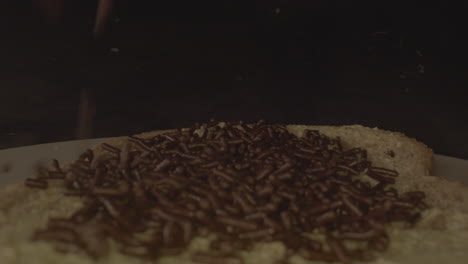 Macro-shot-of-chocolate-sprinkles-falling-on-buttered-slice-of-bread