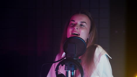 mujer cantando en el micrófono en el estudio de grabación