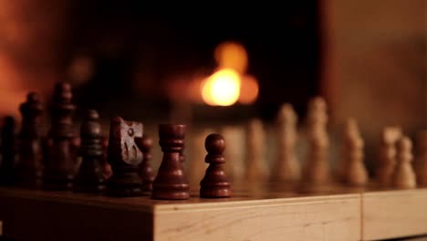 chess game set up on a table in front of a burning fire