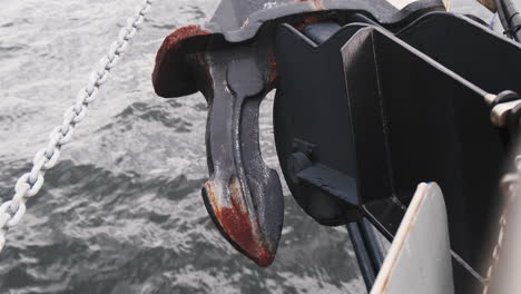 rusty anchor retracted on ship, ocean water and waves in the background