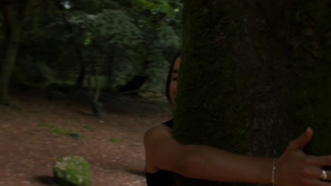 manos femeninas abrazando un gran árbol, moviéndose para revelar una mujer hermosa