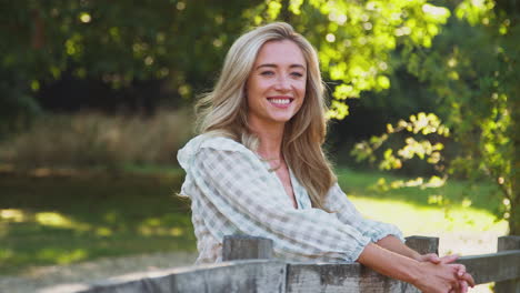 portret van casual gekleed jonge vrouw leunend op het hek op een wandeling in het platteland