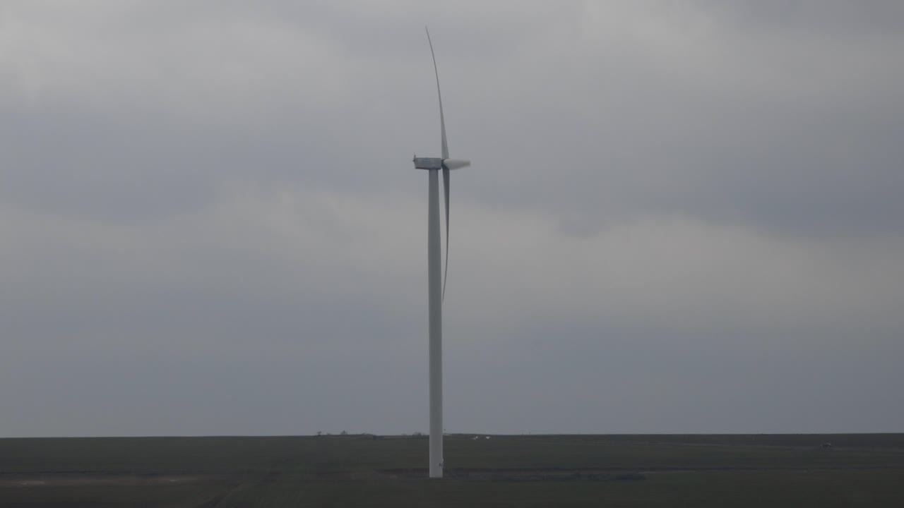 Side View Of Wind Turbine On Field With Cloudy Sky In Background. full shot