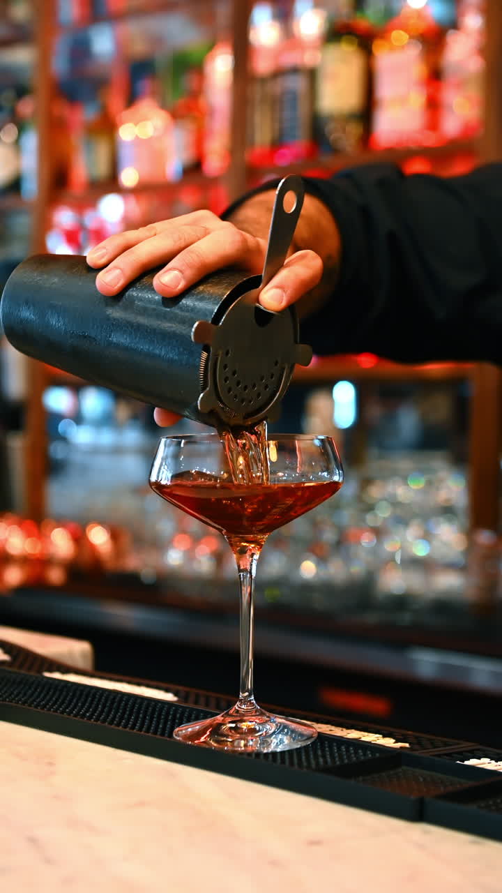 Red cocktail on bar counter. A vibrant red cocktail stands on the bar with colorful bottles glowing behind