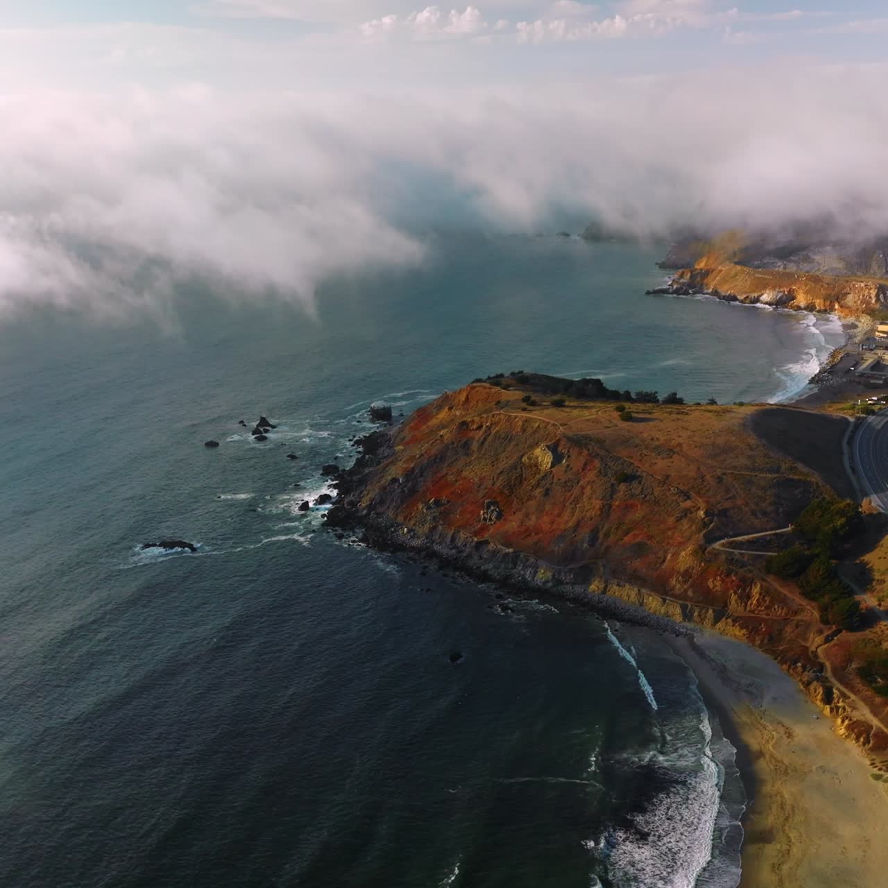 Beautiful rocky coastline of Montara, California, USA. Thick fog slowly moving on city from waters of Pacific. Top view