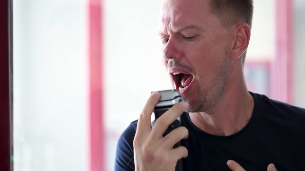 Portrait of carefree handsome man shaving and singing in bathroom 4k movie