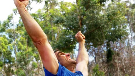 hombre feliz levantando las manos y sonriendo en el campamento de entrenamiento