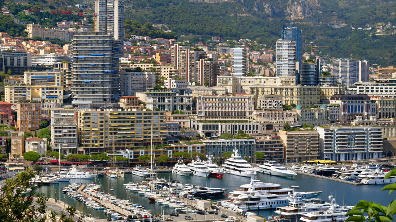 Aerial view of white boats docked in the Monaco Marina with the skyline on the background