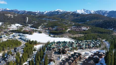 aerial footage of big sky shows condos tucked into a snowy forest landscape, with white roofs, wooded lots, and scenic mountain backdrops filling the quiet montana winter atmosphere