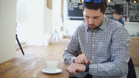 hombre comprobando el reloj inteligente en la cafetería