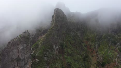 drone shot moving forwards over the cliffs of nuns valley in madeira. thin clouds moving up the peaks.