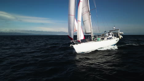 aerial view low and close in front of a sailboat sailing on the gulf of alaska