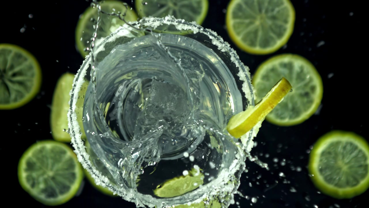 Cubetto di ghiaccio che schizza in un bicchiere da cocktail con lime e bordo di sale