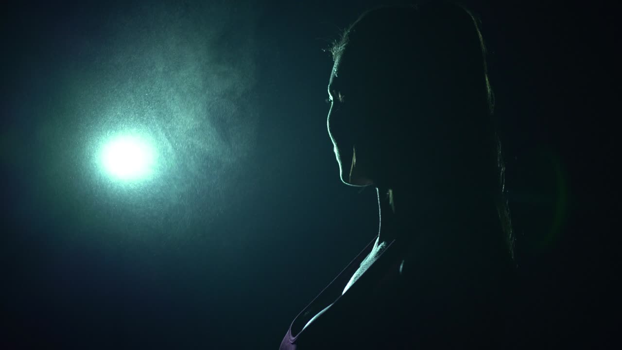 The young woman preparing for taking heavy barbell in the dark room. slow motion