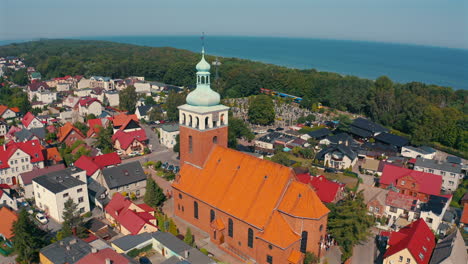 drone flying above the church in jastarnia, poland with baltic sea in the background