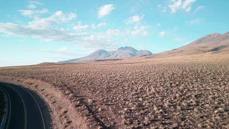 drone saliendo de una carretera en el desierto chileno yendo a un volcán con un cielo nublado