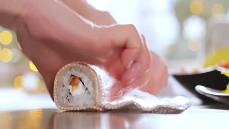 making sushi at home kitchen. woman hands rolling homemade sushi.