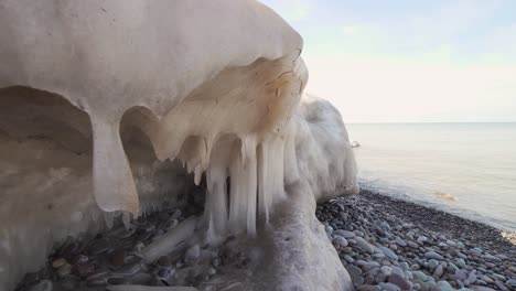 ice cavern on the edge of pebble beach slowly melting in 4k