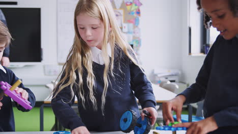 Drei-Grundschulkinder-Arbeiten-In-Einem-Klassenzimmer-Mit-Spielzeugbauklötzen-Zusammen,-Nahaufnahme