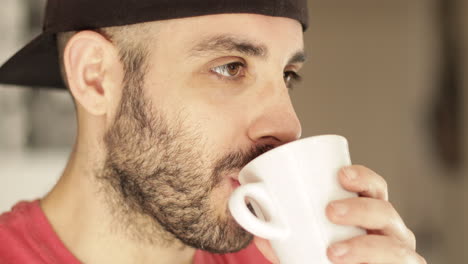 Smiling-caucasian-man-drinks-a-cup-of-tea-or-coffee-indoor