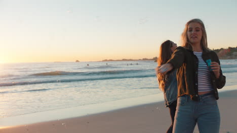 girl friends blowing bubbles on beach at sunset having fun summer playing by the sea enjoying friendship