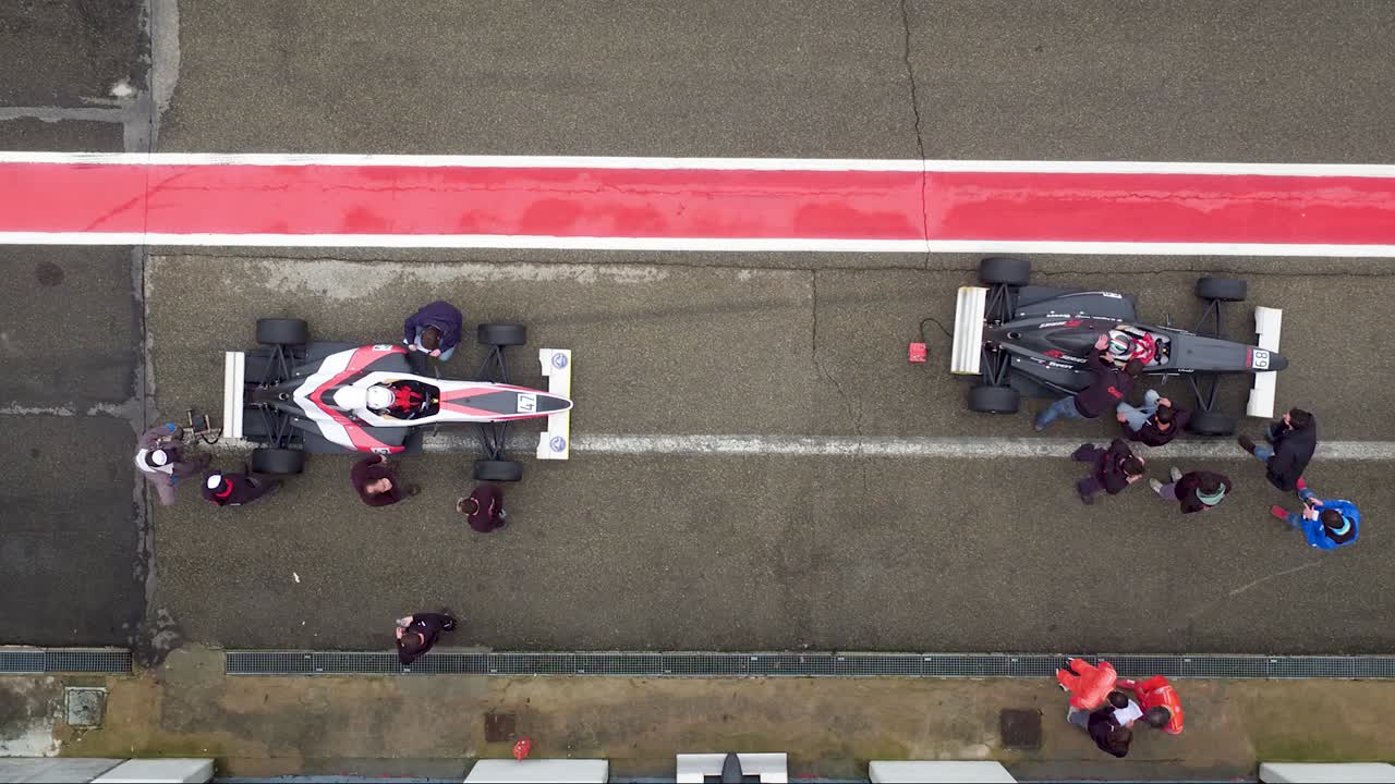 Race cars stopped in pitstop making adjustments for racing. Top view.