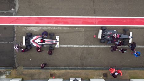 race cars stopped in pitstop making adjustments for racing. top view.