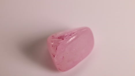 a rose quartz stone spins smoothly on a white surface, showcasing its polished texture and soft pink hue