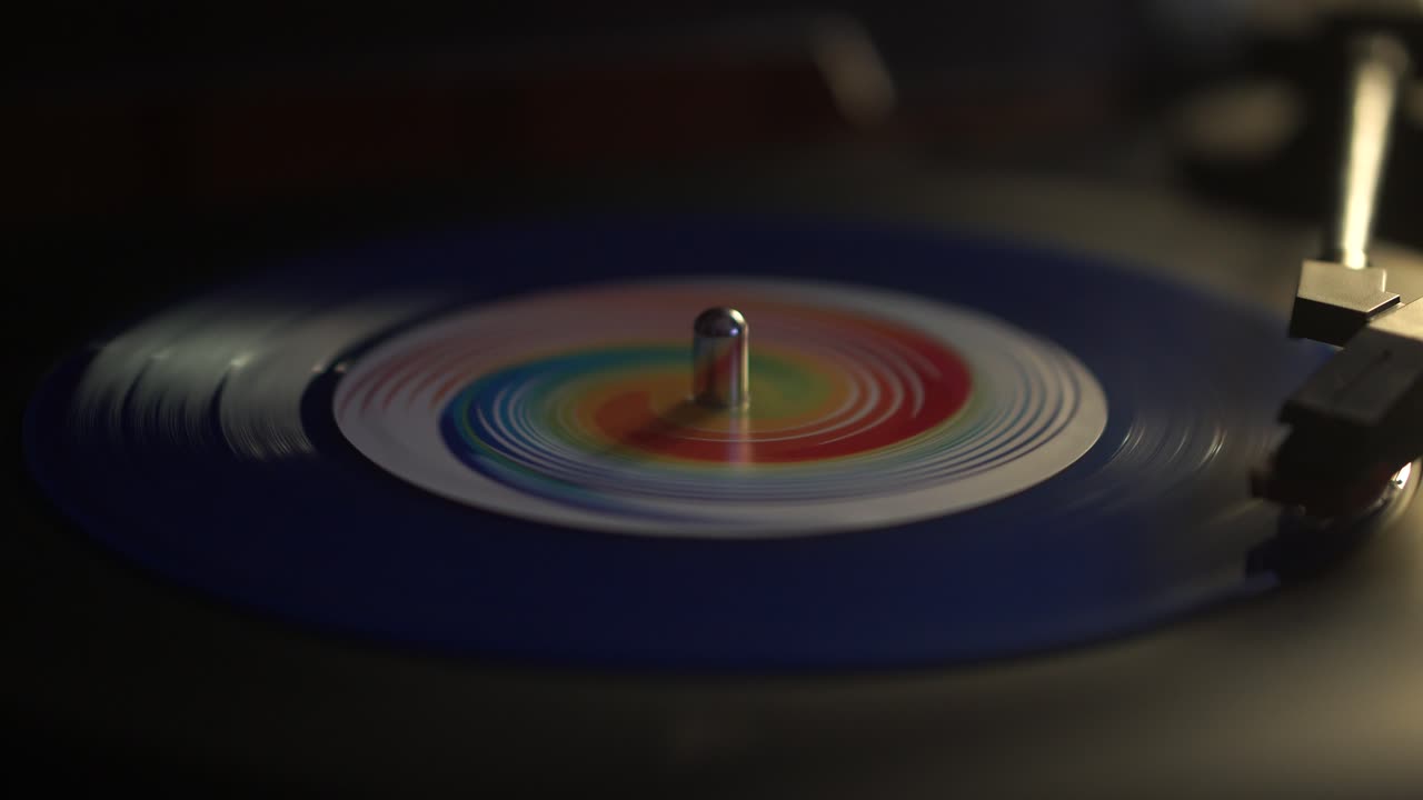 Avvio della riproduzione di un singolo disco in vinile blu su giradischi, primo piano