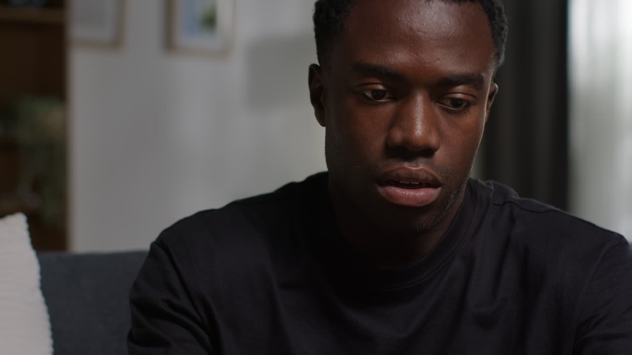 Unhappy And Depressed Young Man Sitting On Sofa At Home Ending Call After Talking On Mobile Phone 2