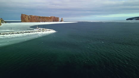 aerial view of percé rock in the winter with ice on the ocean